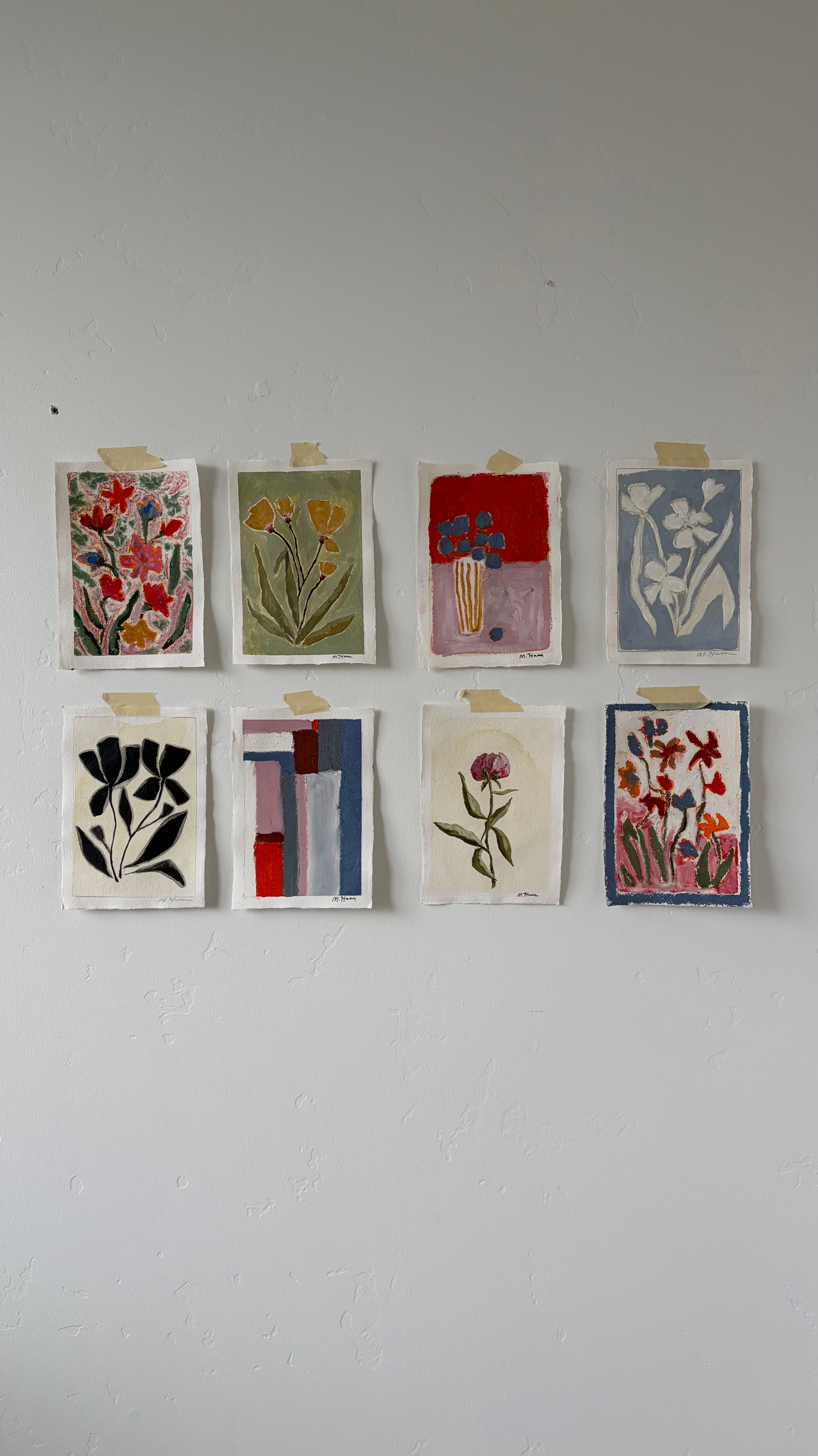 Set of eight small floral and abstract paintings on a white wall.